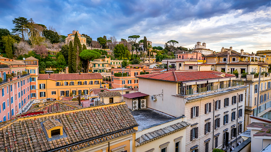 A suggestive and idyllic view over the rooftops and terraces of the Piazza di Spagna district (Spanish Steps Square district), in the historic heart of Rome. On the horizon the famous Pincio Gardens, one of the most visited and loved places in Rome, the culmination of the west side of Villa Borghese, the largest public park in the Italian capital. From the Belvedere of the Pincio Gardens you can enjoy a breathtaking 180-degree view of the historic center of Rome, in the setting of some of the most beautiful gardens in the city. In 1980 the historic center of Rome was declared a World Heritage Site by Unesco. Wide angle image in 16:9 ratio and high definition quality.