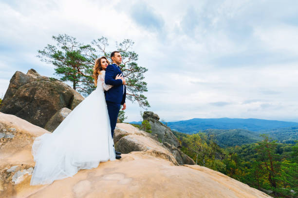 istock The bride embraces the groom from the back side on the rocks. th 1478675788