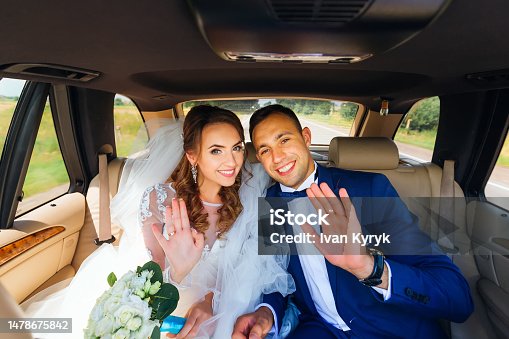 istock the newlyweds sit in the car and waving their hands 1478675842