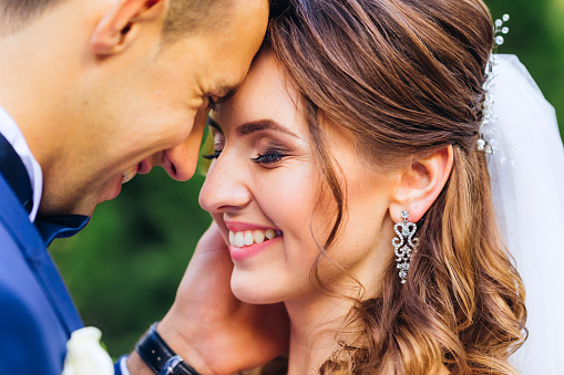 Close-up of newlyweds who lean their heads to each other and smile