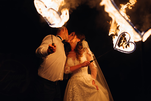 newlyweds kiss and hold a metal heart in the fire