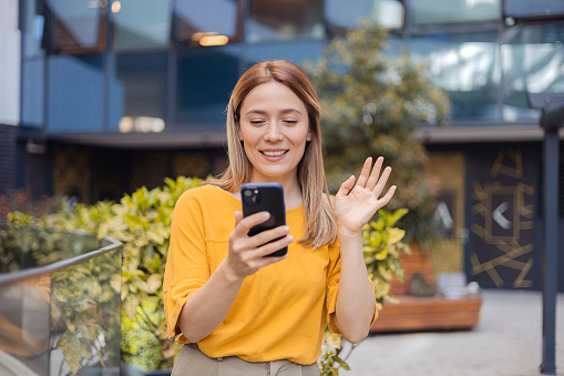 Businesswoman waving on video call through smart phone