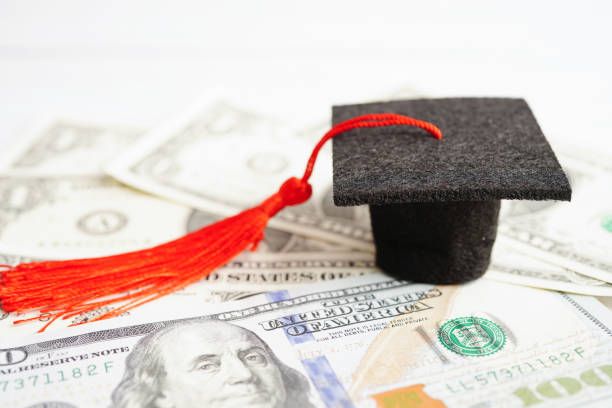istock Graduation gap hat on US dollar banknotes money, Education study fee learning teach concept. 1478680520