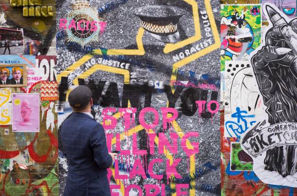 Man looking at a mural on Brick Lane, London. The mural that deals with racial issues