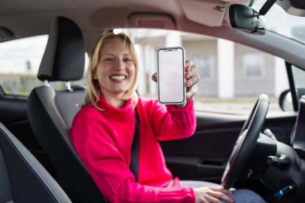 istock Young woman in a driver's seat, showing a white mobile screen 1478682830
