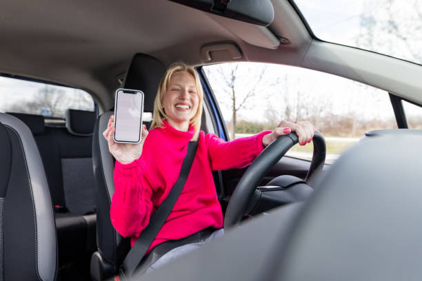 istock Young woman in a driver's seat, showing a mobile screen 1478682932