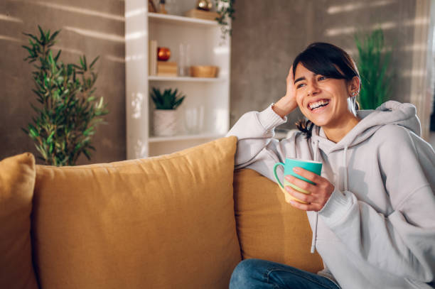 istock Beautiful woman using smartphone and drinking coffee on the sofa at home 1478683125