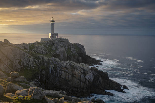 istock Punta Nariga Lighthouse on the cliff under the sunrays piercing through the cloudy sky in Spain 1478690207