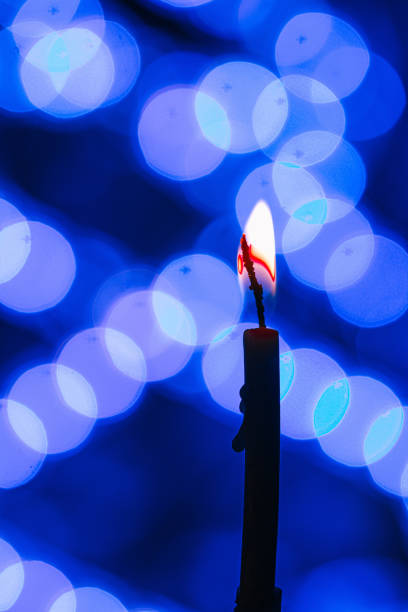 istock Vertical shot of a burning candle on blue blurred bokeh background 1478691781