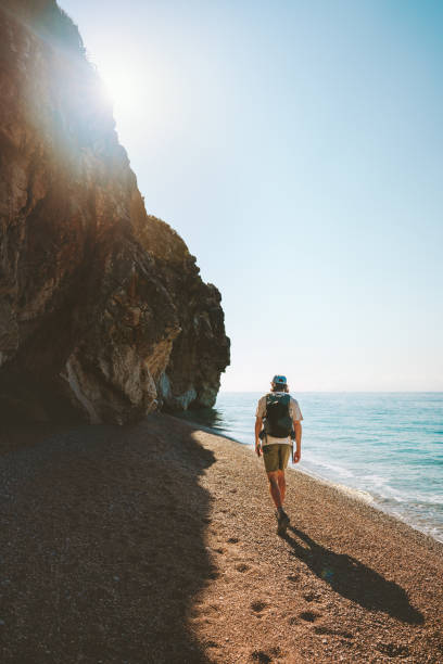 istock Man tourist with backpack walking on empty beach traveling solo active vacations outdoor 1478692139