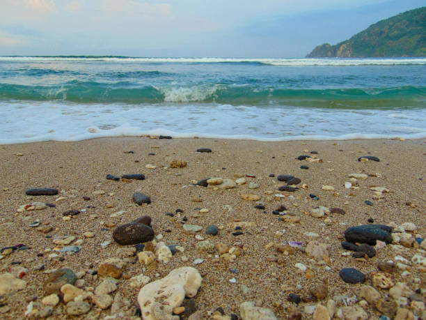 stock photo of stones on the beach sand hit by the waves. very suitable for use as wallpaper or background