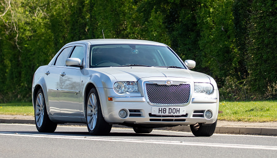 Bicester, Oxfordshire, UK - April 15th 2022. 2008 silver Chrysler 300 car driving on an English country road