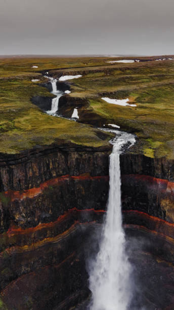 toma aérea vertical de una cascada en islandia con rocas texturizadas y corriente de agua - water waterfall sky seascape fotografías e imágenes de stock