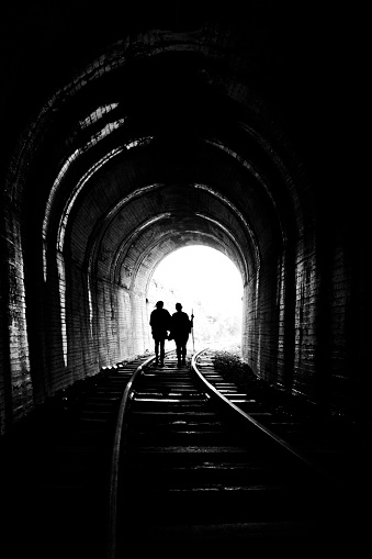 Two friends inside a tunnel heading to the light.