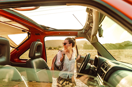 A young woman gets into a car after taking a break during a road trip