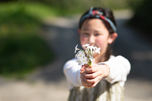 girl holding out white flowers