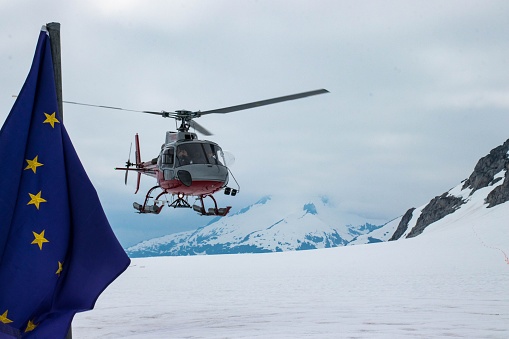 Juneau, United States – July 12, 2022: A Helicopter Landing on the Mendenhall Glacier in Alaska with the EU flag