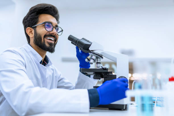 istock Smiling doctor working in modern laboratory research scientist examines substance under microscope. 1478718169