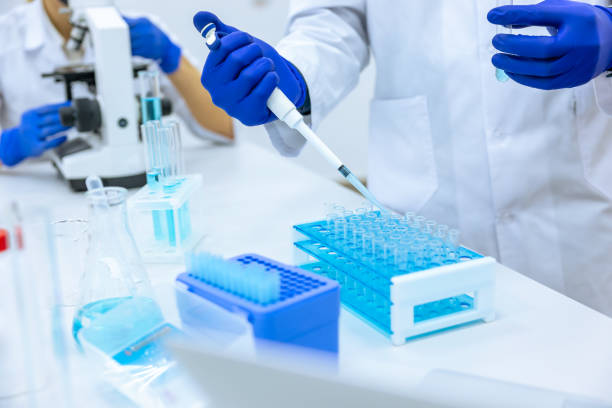 istock Unrecognizable scientist dripping blue liquid from pipette into test tube at table in laboratory. 1478718567