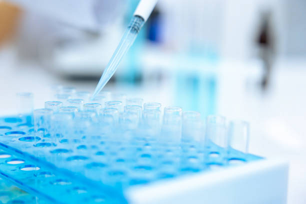 istock Unrecognizable scientist dripping blue liquid from pipette into test tube at table in laboratory. 1478718595