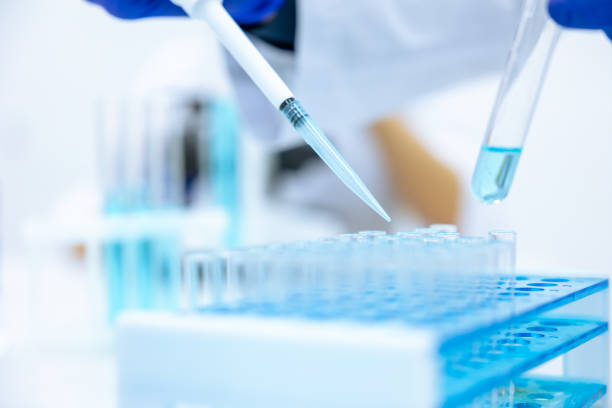 istock Unrecognizable scientist dripping blue liquid from pipette into test tube at table in laboratory. 1478718602