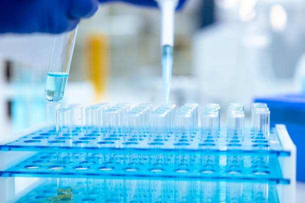 istock Unrecognizable scientist dripping blue liquid from pipette into test tube at table in laboratory. 1478718612