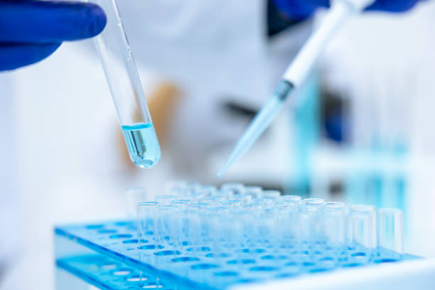 istock Unrecognizable scientist dripping blue liquid from pipette into test tube at table in laboratory. 1478718629