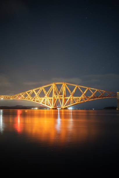 istock Scenery of the famous Forth Rail Bridge illuminated by night lights reflected in water in Scotland 1478721658