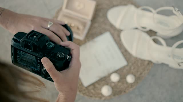 Slow-motion shot of a wedding photographer taking photos of wedding invitations, shoes, and jewelry