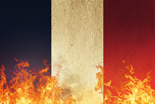 Fire and flames consume the national flag of France.