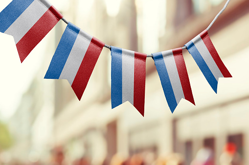 A garland of Netherlands national flags on an abstract blurred background.