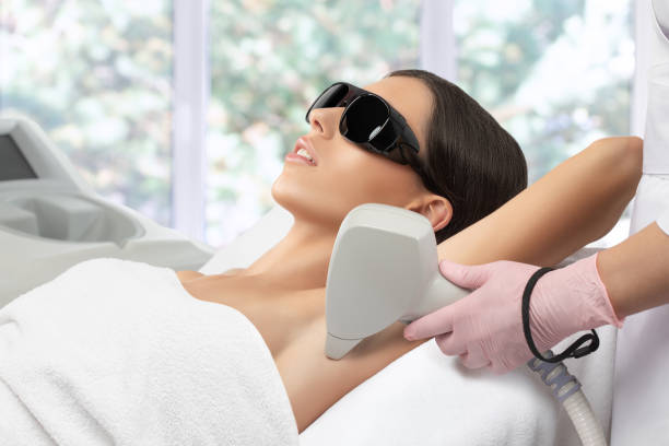 Elos epilation hair removal procedure on a womans body. Beautician doing laser rejuvenation in a beauty salon. Removing unwanted body hair. Hardware ipl cosmetology stock photo