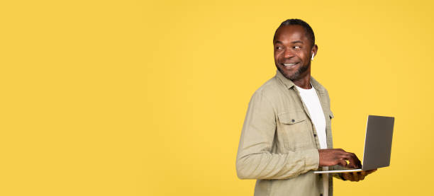 istock Glan adult black man in wireless headphones typing on computer, chatting, look back at empty space 1478730259