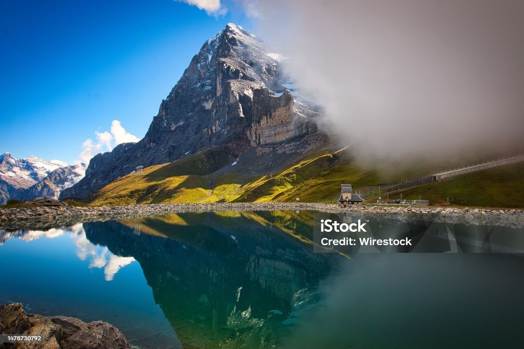 Scenic shot of Eiger Mountain reflecting on a small lake under a blue sky in Switzerland A scenic shot of Eiger Mountain reflecting on a small lake under a blue sky in Switzerland Eiger Stock Photo