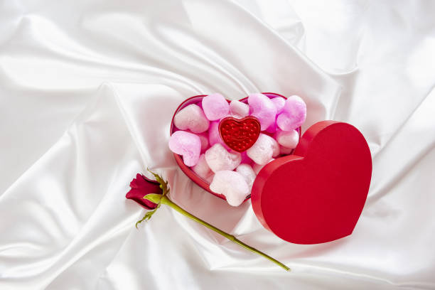 A heart-shaped box with heart-shaped cookies on a white textile