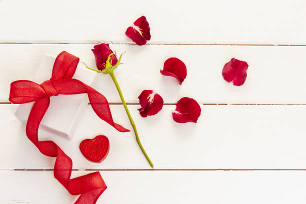 Red rose petals and a gift box with a bow for the Valentines Day
