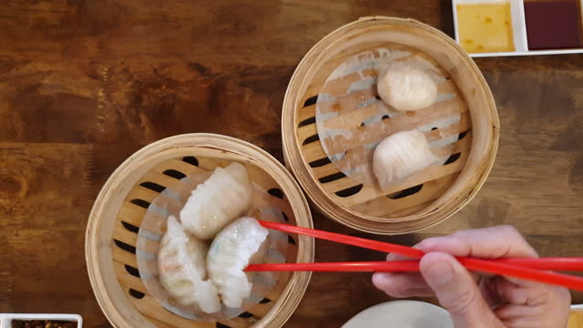 Hands chopsticks family eating dim sum Chinese breakfast food stuffed dumpling