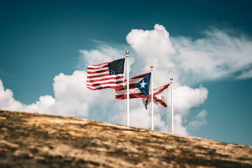 Marfa, TX: US and Texas Flags Blowing in Blue Sky, Marfa Water Tower. Copy space available.