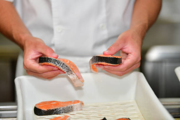 A selective focus shot of cook's hand with fresh raw fish slices