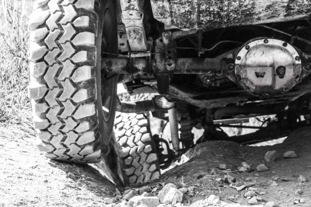 istock Grayscale closeup of high-steer crossover conversion on a dusty road yellow grass background 1478736454