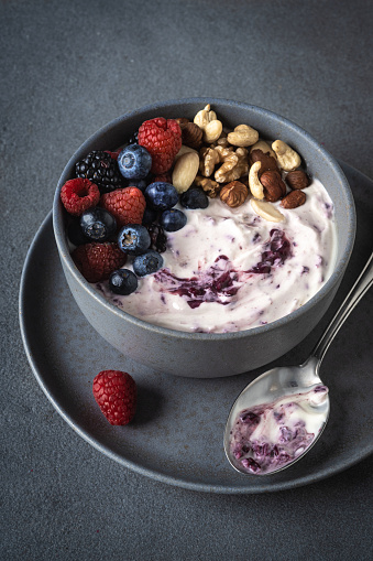 Yoghurt dessert with berries and nuts on gry stone background