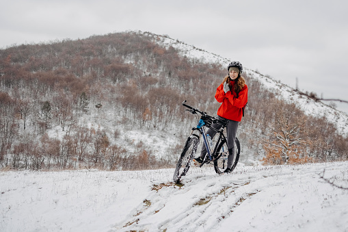 Woman riding a bicycle on a snowy forest road