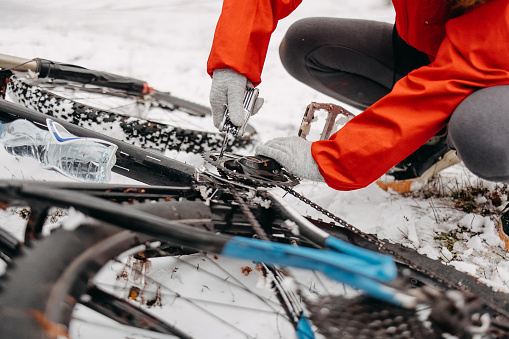 Woman repairs her bicycle in a snow-covered forest