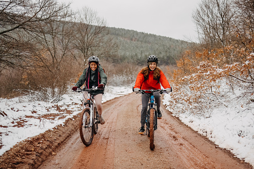 Women are riding their bicycles on a muddy road in the forest