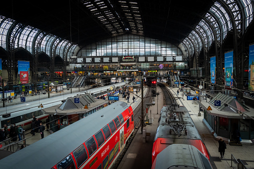 Panoramic view across the trains, platforms and commuters under the wrought iron arches of Hamburg’s Hauptbahnhof central railway station, Germany.