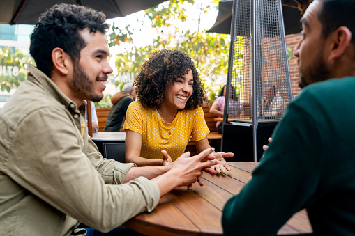 Group of Latin American friends looking very happy while talking at a fast food restaurant