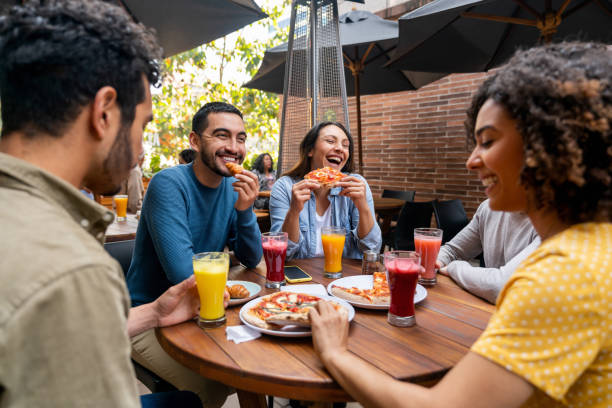 istock Happy friends eating pizza at a restaurant while having fun 1478742897