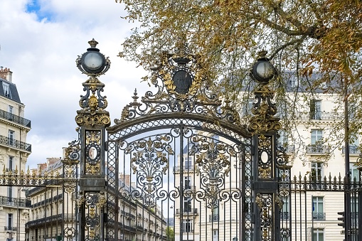 Paris, in the beautiful parc Monceau, the golden wrought iron grid, with typical buildings in background