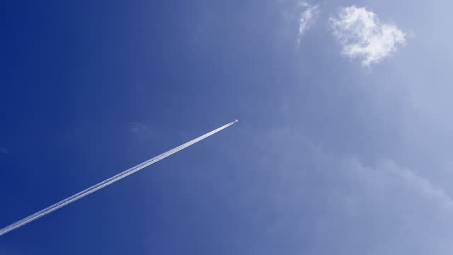 An airplane flying across the blue sky with jet contrail. Cloudscape, Japan.