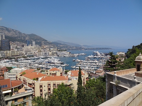 An aerial view of the cityscape of Monaco and the harbor filled with yachts on a sunny day